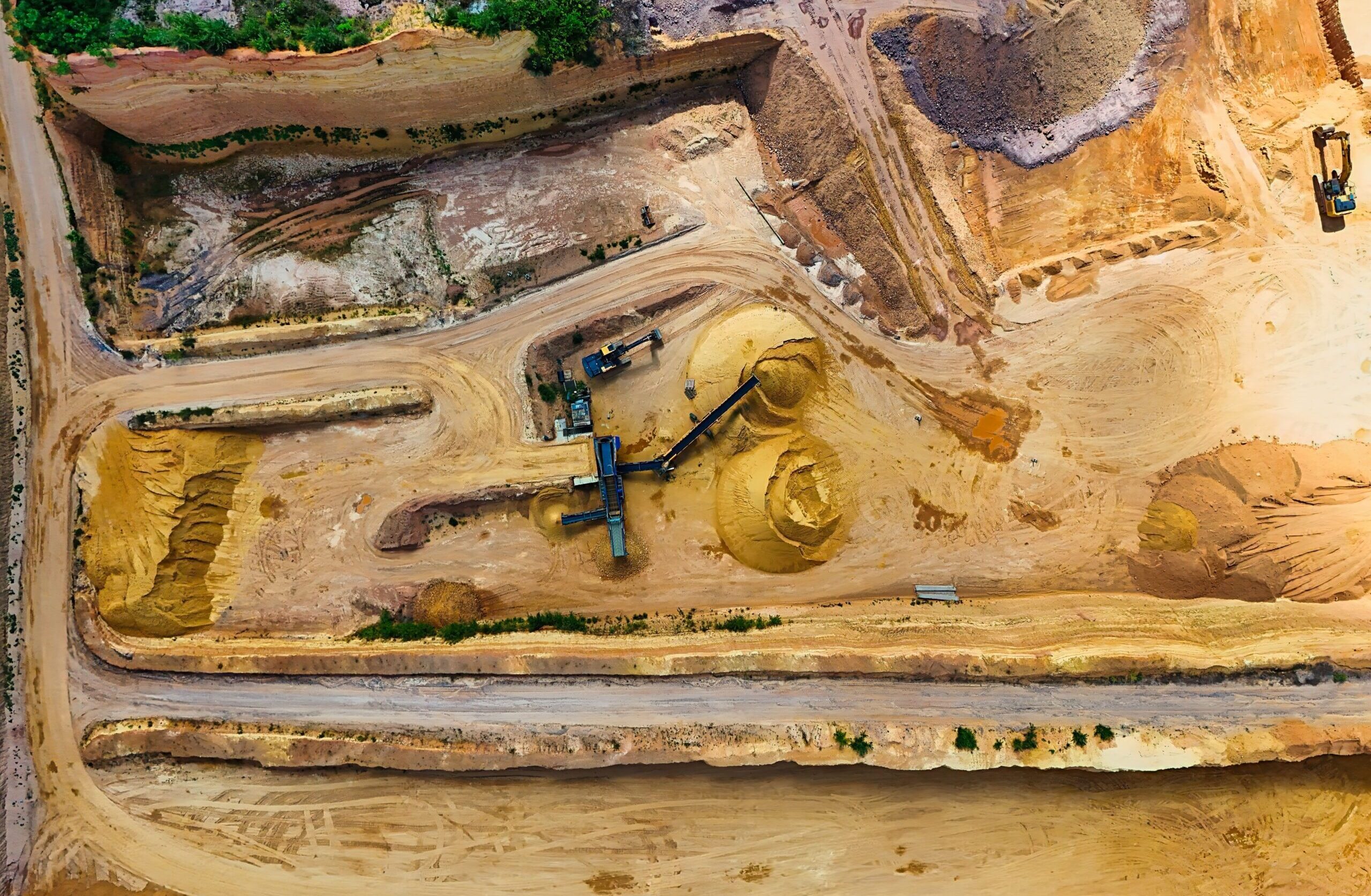 Aerial shot of a quarry with machinery extracting and processing materials.